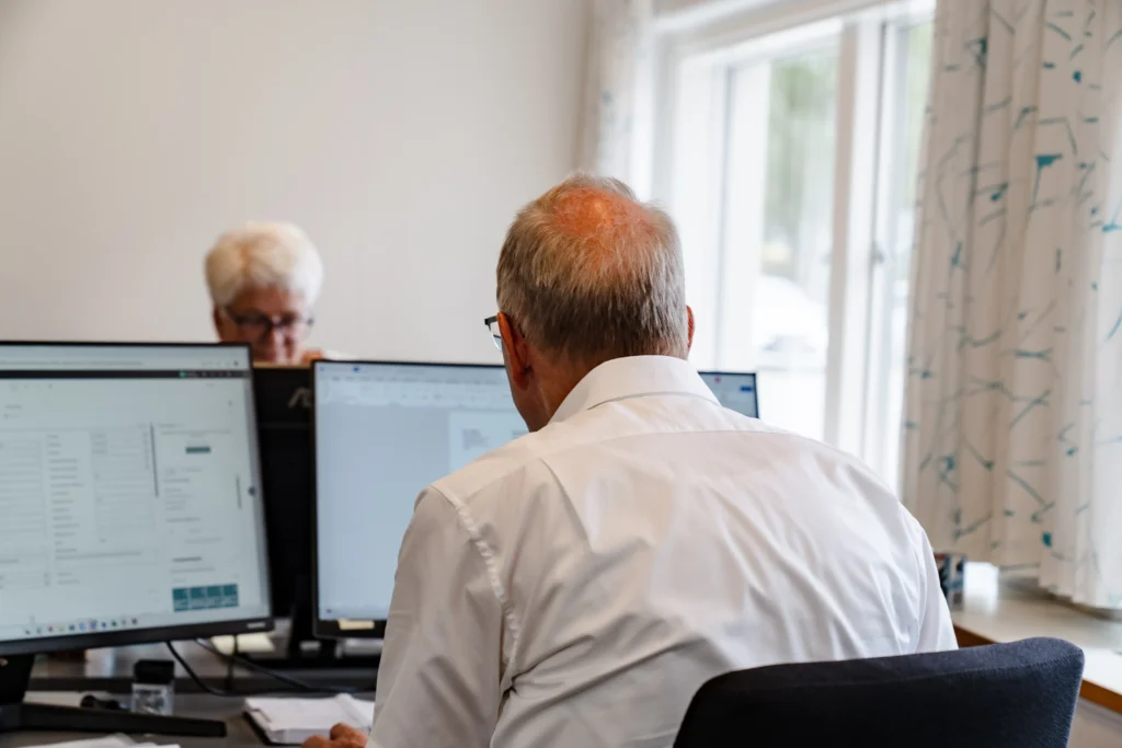 An older man and woman sitting at a desk working.